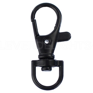 May include: Black metal swivel snap hook with a D-ring. The hook is closed and ready to be attached to a keychain, bag, or other item.