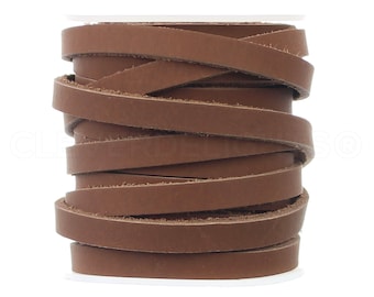 May include: A roll of brown leather cord, approximately 1/4 inch wide, is wound around a white spool. The leather cord is a natural brown color and has a smooth, polished finish.