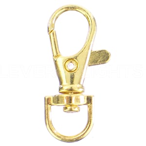 May include: Gold-toned metal swivel clasp with a D-ring. The clasp is designed to attach to a keychain, bag, or other item.