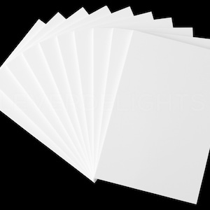 May include: A fan of white rectangular sheets of paper against a black background. The paper is arranged to show the edges of each sheet, creating a layered effect. The paper appears to be clean and unused.
