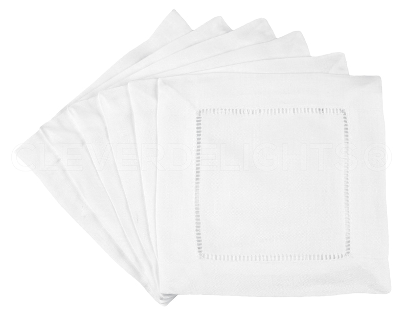 May include: Set of white linen napkins with a delicate embroidered border. The napkins are folded and stacked, showcasing the intricate detail of the stitching.
