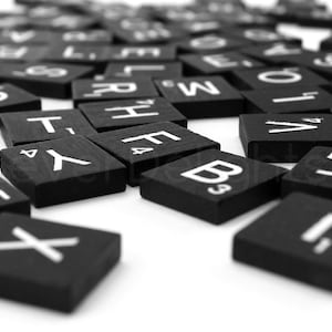 May include: Black letter tiles with white letters on them, scattered on a white surface. The letters include A, B, F, I, L, M, O, R, T, V, X, and Y.