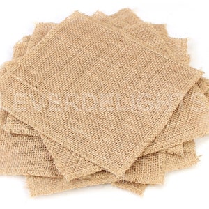 May include: A stack of square burlap fabric pieces. The fabric has a coarse, woven texture and a natural tan color. The edges of the squares are slightly frayed, giving them a rustic appearance. The pieces are arranged in a slightly overlapping pattern.