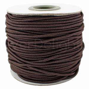 May include: A spool of brown elastic cord, wound tightly on a white cardboard spool.