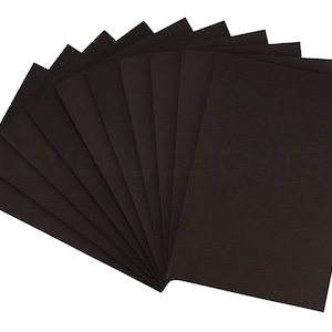 May include: A pack of 10 black sheets of craft paper, fanned out to show the texture of the paper.