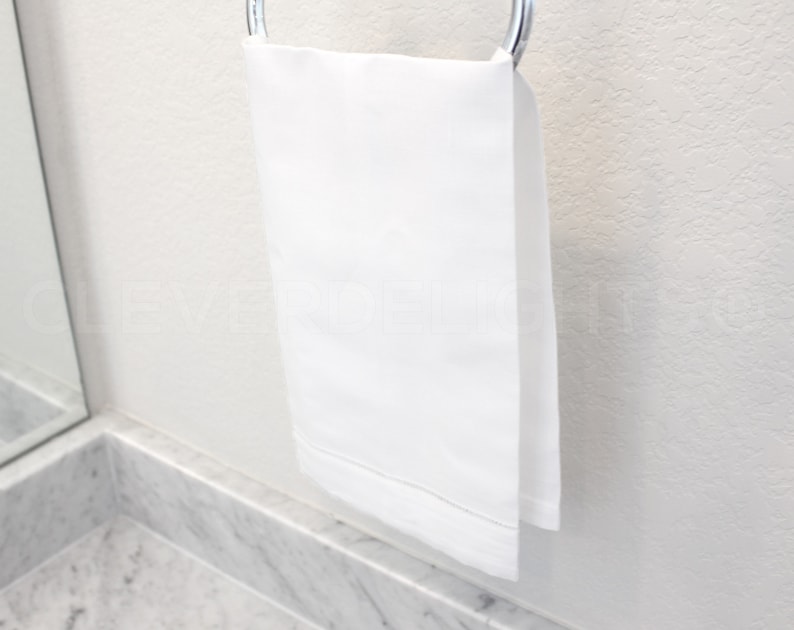 May include: A white bath towel hanging on a silver towel rack.