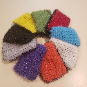 May include: A set of ten colorful crocheted dishcloths with a black trim. The dishcloths are arranged in a circle, with the colors yellow, green, red, blue, gray, purple, orange, and black.