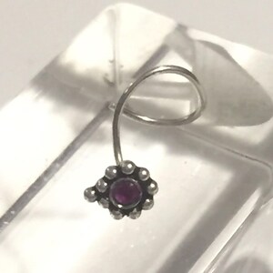 May include: A silver nose ring with a small purple gemstone set in a flower-shaped design.