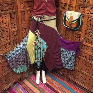 May include: A multi-colored patchwork skirt with a burgundy top and a brown leather bag. The skirt is made of different fabrics and has a layered design. The top is a simple, solid color with a v-neck. The bag is a small, crossbody style with a flap closure.