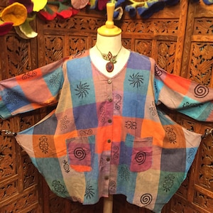 May include: A colorful, patterned, button-up shirt with a loose fit and long sleeves. The shirt is made of a soft, lightweight fabric and features a variety of geometric and floral designs in shades of blue, orange, pink, and brown.