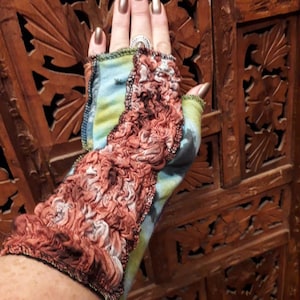 Op de afbeelding: Een paar vingerloze handschoenen met een kleurrijk, tie-dye patroon. De handschoenen zijn gemaakt van een zachte, rekbare stof en hebben een gerimpelde rand.