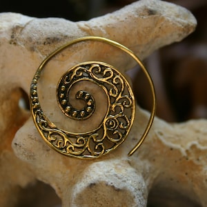 May include: A gold-toned spiral earring with a delicate filigree design. The earring is made of metal and has a hoop shape.
