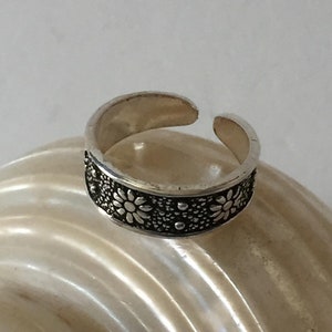 May include: A silver ring with a floral design. The ring is adjustable and has a delicate, feminine look.