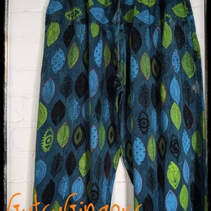 May include: Blue denim pants with a green and blue leaf pattern. The pants have a drawstring waist and a relaxed fit.