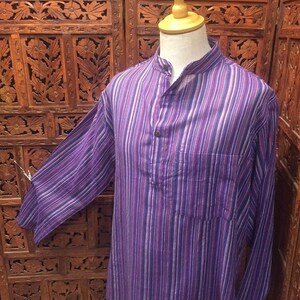 May include: A long-sleeved, purple and white striped shirt with a mandarin collar and a single button closure. The shirt has a pocket on the left side.