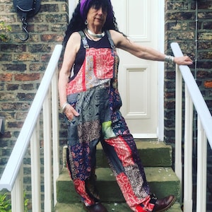 Peut inclure: Une femme portant un foulard violet et une combinaison en patchwork à motifs floraux. Elle est debout sur un escalier avec une rampe blanche.