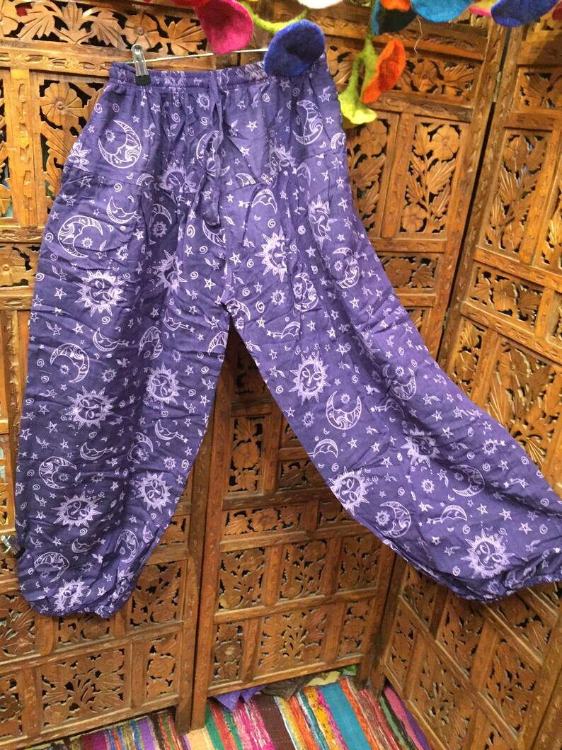 May include: Purple cotton pants with a white sun and moon print. The pants have an elastic waistband and a drawstring.