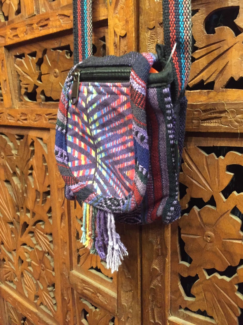 Pode incluir: Uma pequena bolsa transversal tecida colorida com fecho de correr e um tassel. A bolsa &eacute; feita de uma variedade de tecidos e tem um padr&atilde;o geom&eacute;trico.