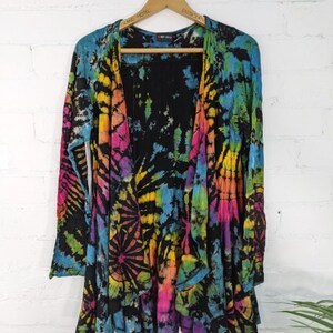 Könnte beinhalten: Ein schwarzer Batik-Cardigan mit einem langen, fließenden Design. Der Cardigan zeigt einen Regenbogen aus Farben, darunter Pink, Blau, Gelb und Grün.