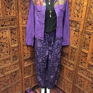 May include: Purple denim jacket with a patchwork collar and purple pants with a moon and star pattern. The pants are loose fitting and the jacket has a button closure.