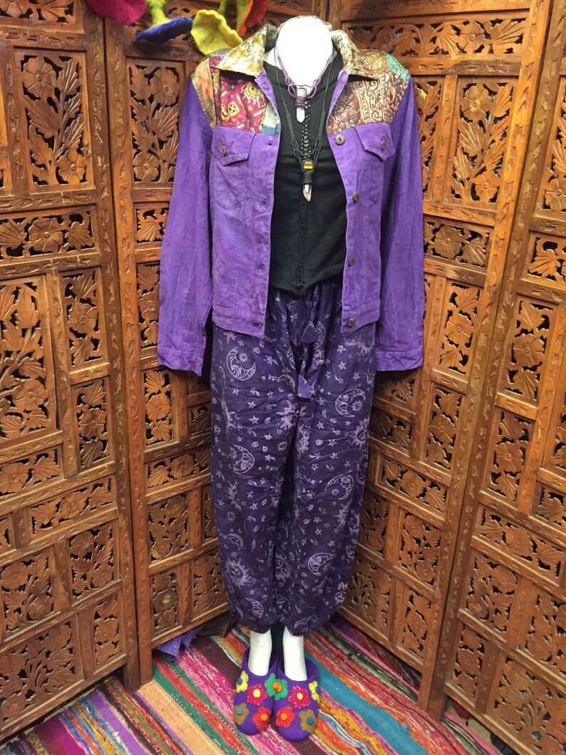 May include: Purple denim jacket with a patchwork collar and purple pants with a moon and star pattern. The pants are loose fitting and the jacket has a button closure.
