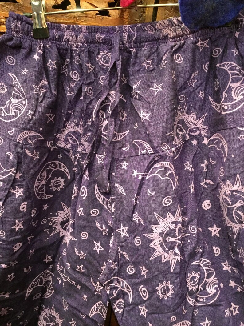 May include: Purple cotton pants with a white print of moons, stars, and suns.