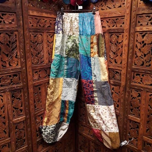 Peut inclure: Pantalon patchwork fait de chutes de tissus colorés. Le pantalon est un mélange de bleus, de verts, d'or et de rouges. Le tissu est un mélange de soie et de coton.