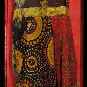 May include: A black and red patchwork dress with a floral print and a circle pattern. The dress has a halter top and a loose, flowing skirt.
