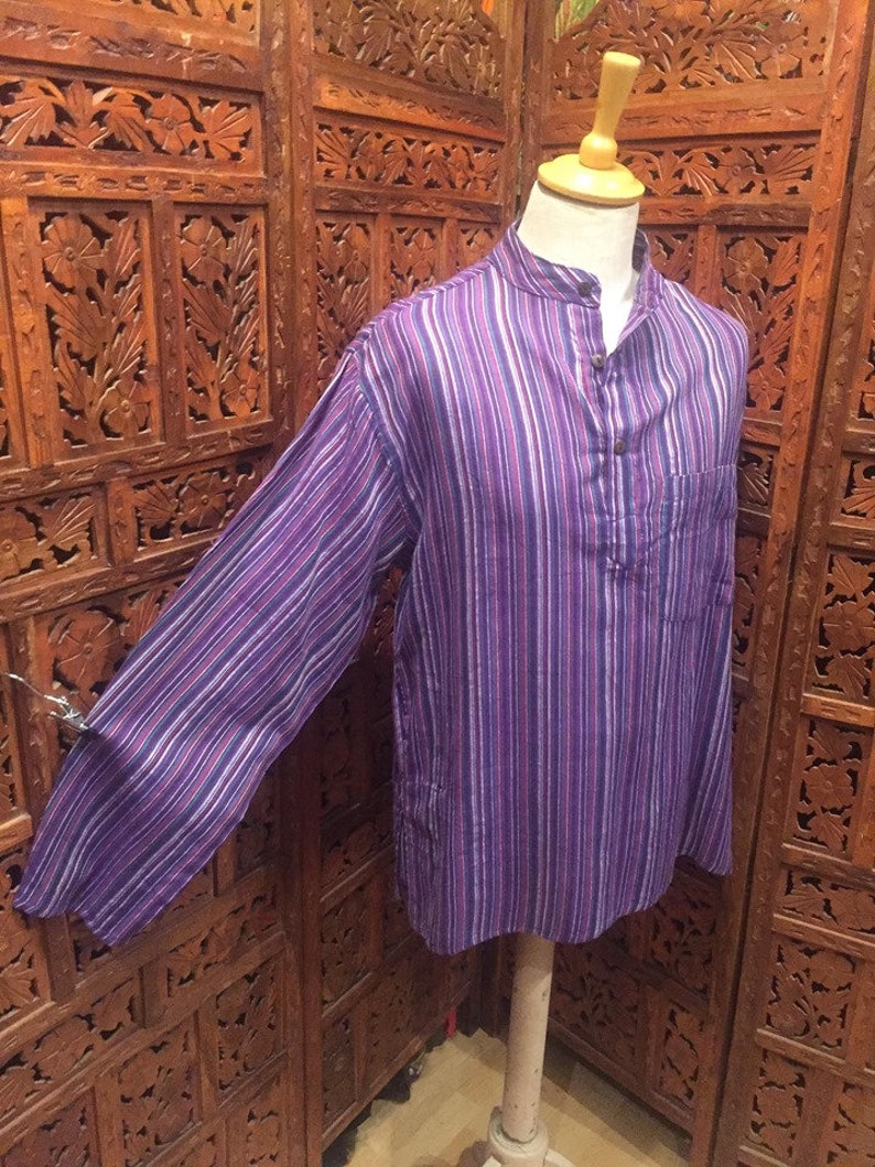 May include: A long-sleeved shirt with a purple and white striped pattern. The shirt has a mandarin collar and a single button closure at the neck.