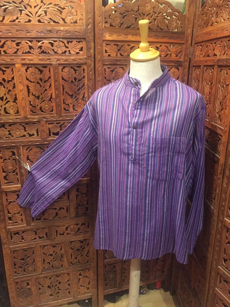 May include: A long-sleeved shirt with a purple, white, and pink striped pattern. The shirt has a mandarin collar and a single button closure.