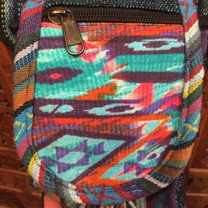 Pode incluir: Uma pequena bolsa transversal tecida colorida com fecho de correr e um tassel de franjas. A bolsa &eacute; feita de uma variedade de tecidos e tem um padr&atilde;o geom&eacute;trico.