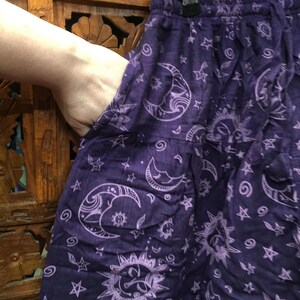 May include: Purple cotton pants with a white moon and star print. The pants have an elastic waistband and a drawstring.