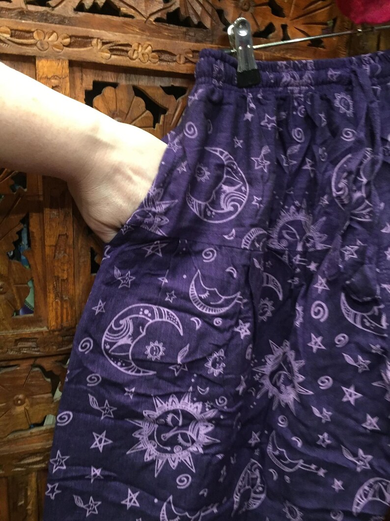 May include: Purple cotton pants with a white moon and star print. The pants have an elastic waistband and a drawstring.