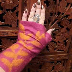 Op de afbeelding: Vingerloze handschoenen in roze en oranje met een bloemenpatroon. De handschoenen zijn gemaakt van een zachte, gebreide stof.