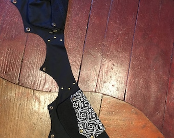Pode incluir: Cinto de lona preto com vários bolsos e um bolso com padrão geométrico preto e branco. O cinto tem ilhós de metal e uma fivela.