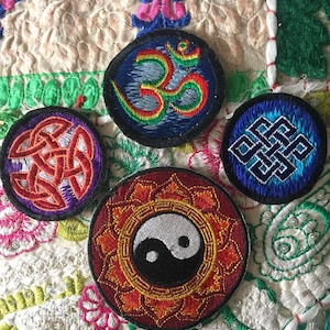 Peut inclure: Quatre patchs brodés avec des symboles spirituels. Les patchs sont circulaires et présentent un nœud celtique rouge et violet, un symbole Om bleu et vert, un symbole yin yang rouge et or et un nœud sans fin bleu et vert.