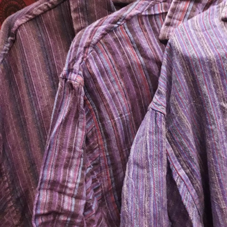 Op de afbeelding: Drie gestreepte shirts in tinten van paars, blauw en rood. De shirts zijn gemaakt van een zachte, geweven stof en hebben een ontspannen pasvorm.