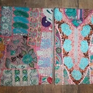 Pode incluir: Uma capa de almofada de patchwork com um design floral rosa, azul e verde. A capa é feita de diferentes tecidos e é decorada com lantejoulas e contas.