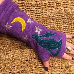 Può includere: Scaldamani in pile viola con un designo di luna e stelle. Lo scaldamani presenta anche una silhouette ricamata di una lepre.