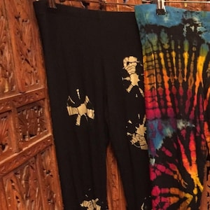 May include: Two pairs of black pants with tie-dye patterns. One pair has a white swirl design, and the other has a rainbow swirl design.