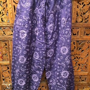 May include: Purple cotton pants with a white sun and moon print. The pants have an elastic waistband and a drawstring.