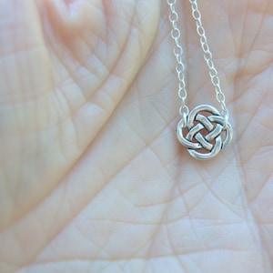 May include: A silver Celtic knot pendant necklace on a silver chain. The pendant is a circular design with intricate knotwork.