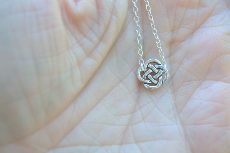 May include: A silver Celtic knot pendant necklace on a silver chain. The pendant is a circular design with intricate knotwork.
