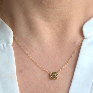 May include: A gold chain necklace with a small, intricate knot pendant.
