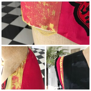 Puede incluir: Primer plano de una tela roja y dorada con un borde deshilachado. La tela tiene un patr&oacute;n de rayas amarillas y rojas. La tela probablemente forma parte de una prenda de vestir, como un vestido o una chaqueta.