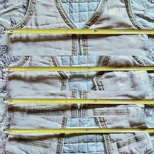 May include: A white vest with a green, red, and white striped trim. The vest has two pockets on the front and is made of a lightweight fabric.