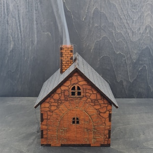 May include: A wooden house-shaped incense burner with a brick chimney. Smoke is rising from the chimney.