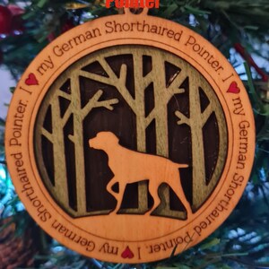 May include: Wooden Christmas ornament featuring a German Shorthaired Pointer dog silhouette. The ornament has a circular design with a forest scene and the text "I love my German Shorthaired Pointer."