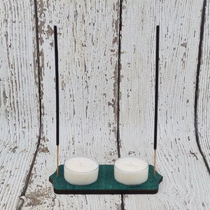 May include: A wooden incense and candle holder with two tealight candle holders and two incense sticks. The holder is painted green and has a natural wood finish.
