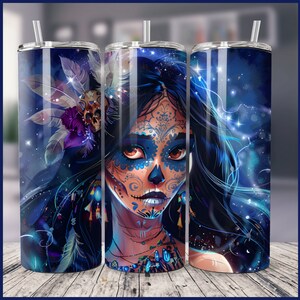 May include: A stainless steel tumbler with a colourful design featuring a woman with a sugar skull face and blue feathers. The background is a dark blue with white stars.